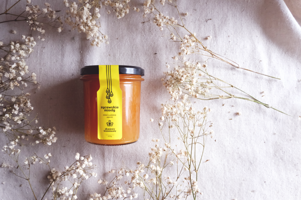 słoik miodu na białym obrusie z gipsówkami
