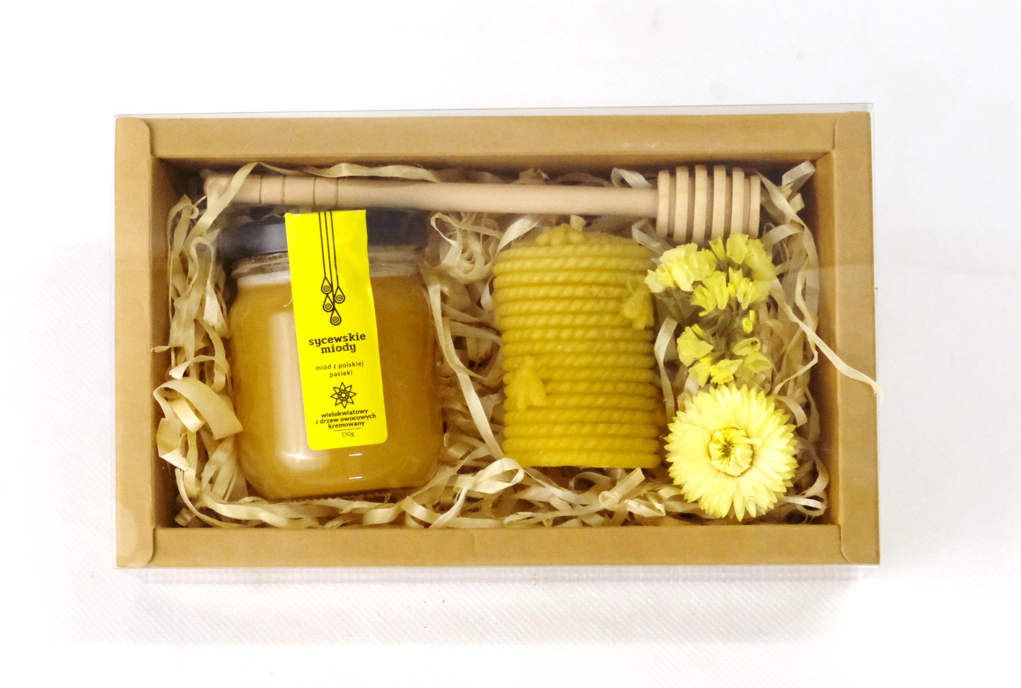 Box prezentowy z małym słoiczkiem miodu, świeczką z wosku pszczelego i drewnianym miodownikiem.