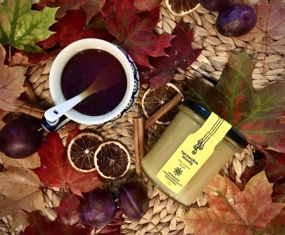 słoik miodu z kubkiem czarnej herbaty na tle jesiennych liści i suszonych pomarańczy